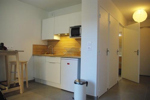 una piccola cucina con armadi bianchi e tavolo di Appartement avec Balcon Immeuble Standing a Lione