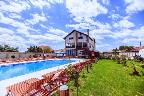 a resort with a pool and chairs and a building at Pensiunea Luminita in Târgu Jiu