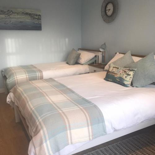 two twin beds in a room with a clock on the wall at Coast 77 B&B in Poole
