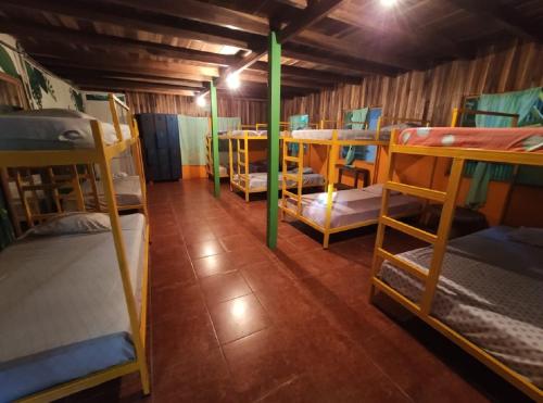 a room with several bunk beds and tables at Madre Selva Hostel in Puerto Viejo