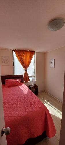 1 dormitorio con cama roja y ventana en DEPARTAMENTO POR DÍA EN LA CIUDAD DE ARICA., en Arica