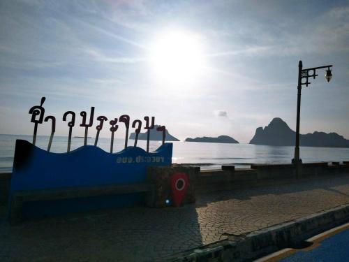 a sign on the beach with the sun in the background at Saan Rak Resort in Prachuap Khiri Khan