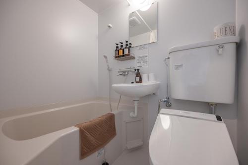 a white bathroom with a toilet and a sink at HOTEL R9 The Yard Isumi in Chōjamachi