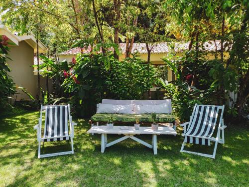 two chairs and a bench in a yard at Casa Kokoro in Pipa