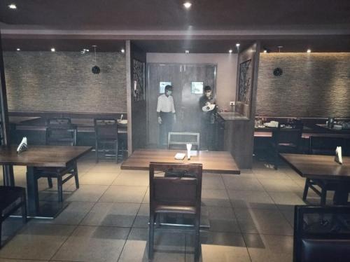 a man standing in a restaurant with tables and chairs at Hotel Elite International in Trichūr