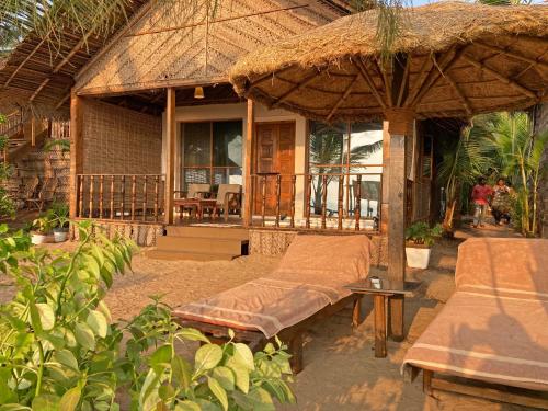 a porch of a house with a bed and an umbrella at Agonda Villas in Agonda