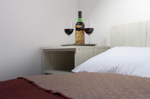 a bottle of wine and two glasses on a table next to a bed at CASA GRETA in Lupeni