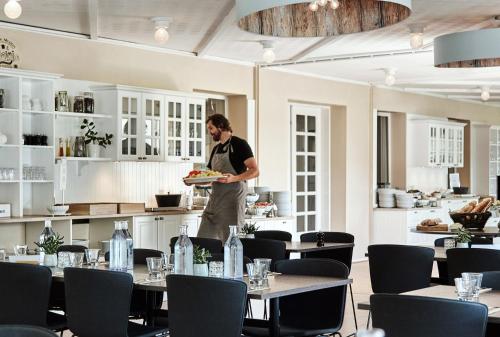 un homme tenant un plat dans un restaurant dans l'établissement Aspenäs Herrgård, à Lerum