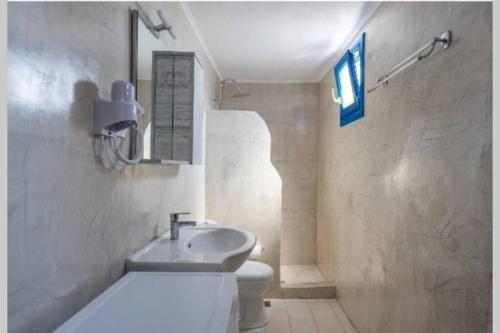 a bathroom with a white toilet and a sink at easy going santorini house in Éxo Goniá