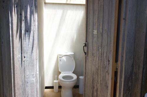 a bathroom with a white toilet in a room at Belle Glamping by the Sea in Katikati