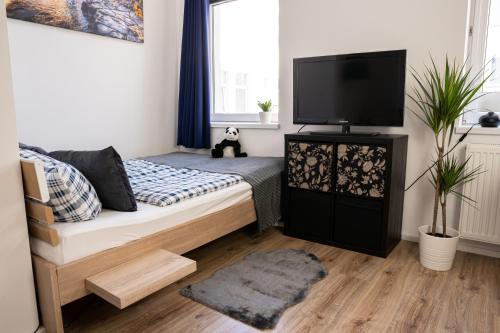 a bedroom with a bed with a flat screen tv at FULL HOUSE Studios - Blue Apartment - WiFi inkl in Magdeburg