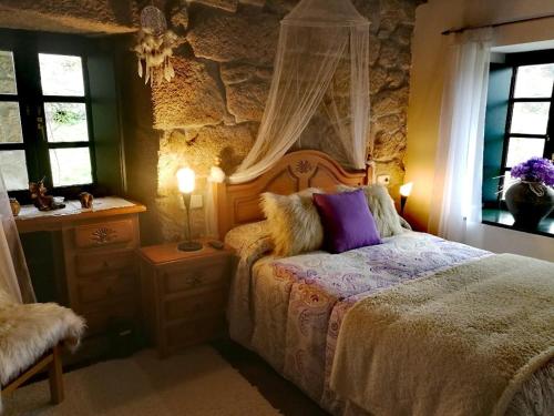 a bedroom with a bed and a stone wall at Caserio de Fontes in Nogueira de Ramuin