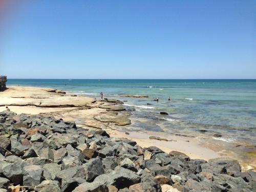 a beach with rocks and people in the water at XYL Holiday Inn in Caloundra