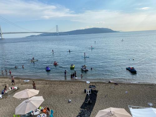 people on a beach with umbrellas at Guesthouse Geragera in Kobe