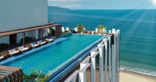 einem Pool an der Seite eines Gebäudes mit Meerblick in der Unterkunft HAIAN Beach Hotel & Spa in Đà Nẵng