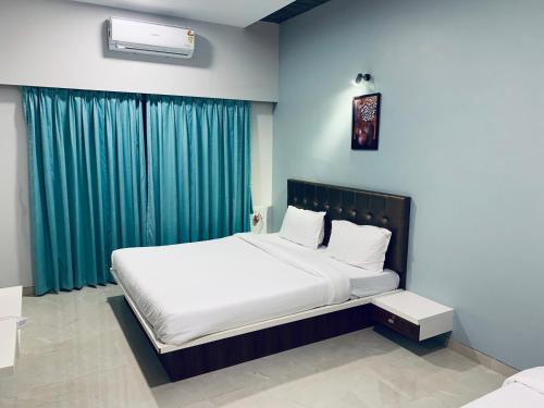a bedroom with a large bed with green curtains at Fortune Resort in Nagaon