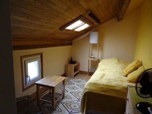 a bedroom with a bed and a window and a table at Au Catalpa in La Chapelle-Faucher