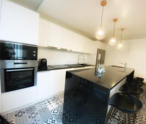 a kitchen with white cabinets and a black counter top at Manoir 1838 à - 3 km du Zoo de Beauval & proche des châteaux in Saint-Aignan