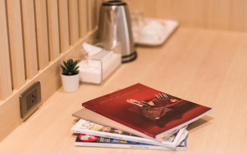 a pile of books sitting on a counter next to a window at La Route Residence Pattaya in Pattaya North
