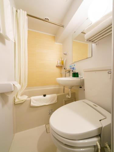 a white bathroom with a toilet and a sink at Super Hotel Ikebukuro-Eki Kitaguchi in Tokyo
