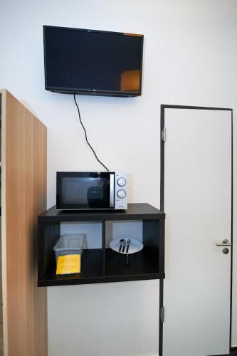 a black shelf with a microwave and a tv on a wall at Goldmarie in Berlin