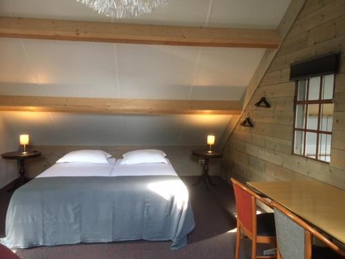 a bedroom with a white bed with two tables and two lamps at Vakantiehuis bij Bedaf in Uden