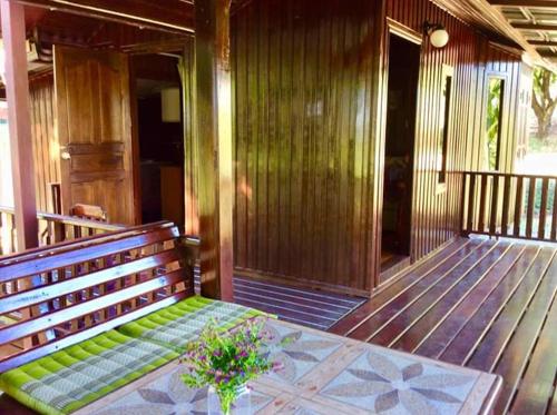 Ban Na Chaliang的住宿－The Green Vale B&B，木门廊,配有长凳和桌子
