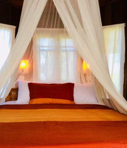 a bedroom with a canopy bed with white curtains at The Green Vale B&B in Ban Na Chaliang