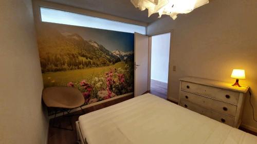 1 dormitorio con 1 cama y una pintura en la pared en FeWo Schneerose, Steibis, en Oberstaufen