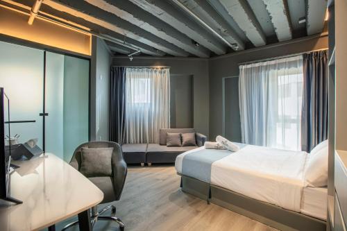 a bedroom with a bed and a desk and a chair at Hotel Calmo Bugis in Singapore