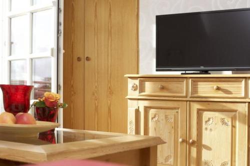 a television on a wooden cabinet with a bowl of fruit at Schimmels Pension in Wustrow