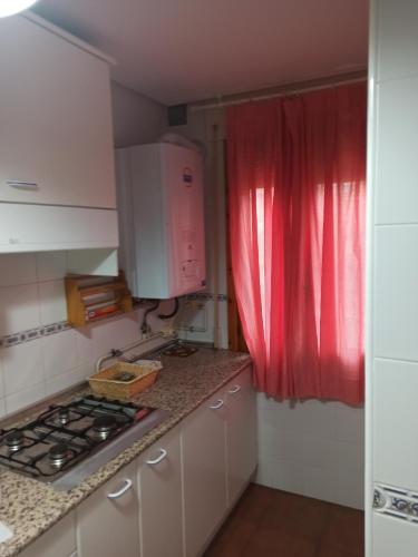 cocina con fogones y cortina roja en Alojamiento rural LA JARA 2, en Robledillo de la Jara