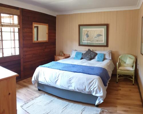 Star Dam Estate - Tranquil Cottage في Lidgetton: غرفة نوم بها سرير كبير وكرسي