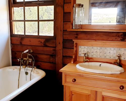 Star Dam Estate - Tranquil Cottage في Lidgetton: حمام مع حوض استحمام ومغسلة وحوض استحمام