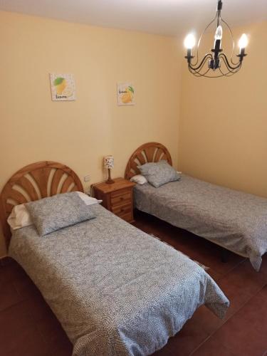 1 dormitorio con 2 camas y lámpara de araña en Alojamiento rural LA JARA 2, en Robledillo de la Jara