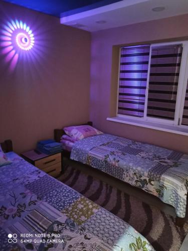 a bedroom with two beds and a window with purple lights at Дачний будинок in Kobelyaky