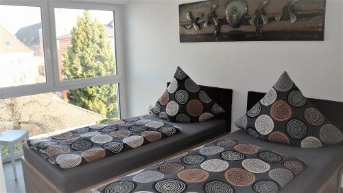 2 camas con almohadas en una habitación con ventana en BodenSEE Penthouse Friedrichshafen, en Friedrichshafen