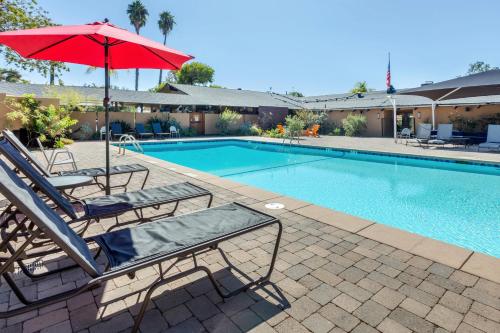 a pool with two lounge chairs and an umbrella at Carlton Oaks Lodge, Ascend Hotel Collection in Santee