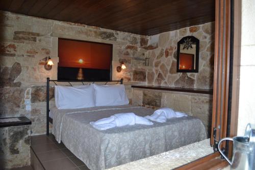 a bedroom with a bed in a stone wall at Katerina Apartments in Káto Zákros