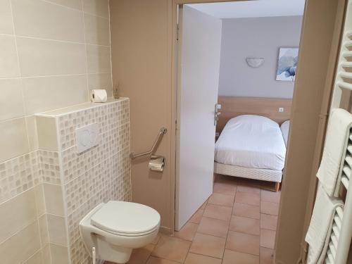 a bathroom with a toilet and a bed at Hôtel Du Commerce in Fécamp
