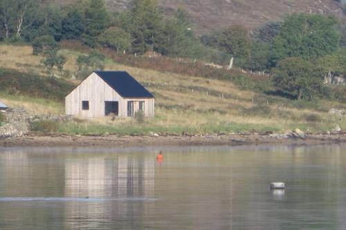 a barn sitting on the shore of a body of water at Beautiful views from right above the water in Dunan