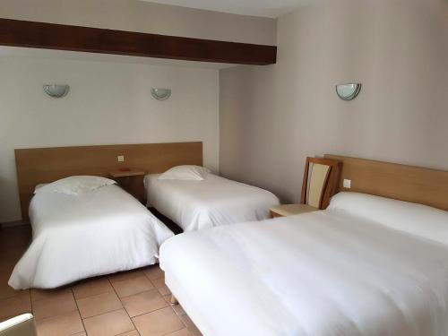 two beds in a hotel room with white sheets at Hôtel Du Commerce in Fécamp