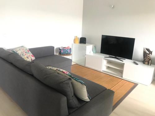a living room with a couch and a flat screen tv at T2 Ferragudo Cosy Beach Apartment in Ferragudo