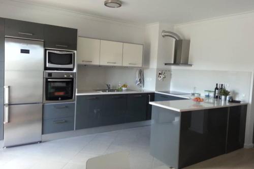 a kitchen with stainless steel appliances and gray cabinets at T2 Ferragudo Cosy Beach Apartment in Ferragudo