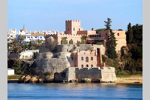 a castle on a hill next to a body of water at T2 Ferragudo Cosy Beach Apartment in Ferragudo