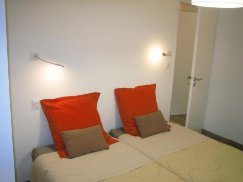 two beds in a room with orange pillows at AGATHE chambres d'hôtes in Guérande