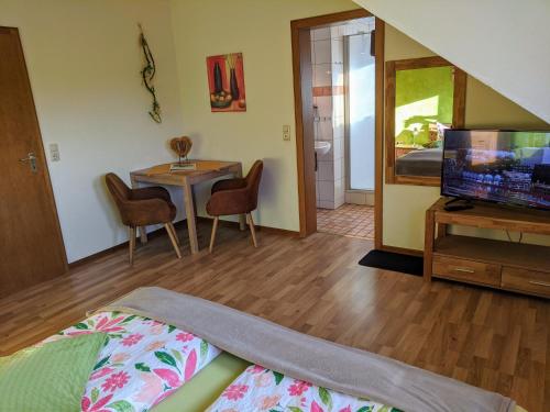 a living room with a television and a table with chairs at Haus am Grasberg in Poppenhausen