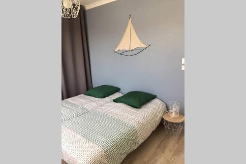 Un dormitorio con una cama con dos almohadas verdes. en Charmante Maison idéalement située, en Saint Gilles Croix de vie