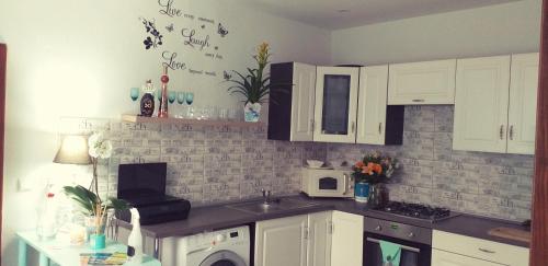 a kitchen with white cabinets and a sink and a microwave at Monato in Poprad