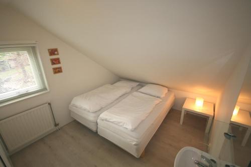 een kleine kamer met een bed en een wastafel bij Fonteinbos in Oudemirdum